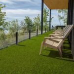 Terrazza moderna con pavimentazione in prato sintetico misto erba Eurogreen, con vista panoramica e sedie da esterno beige.